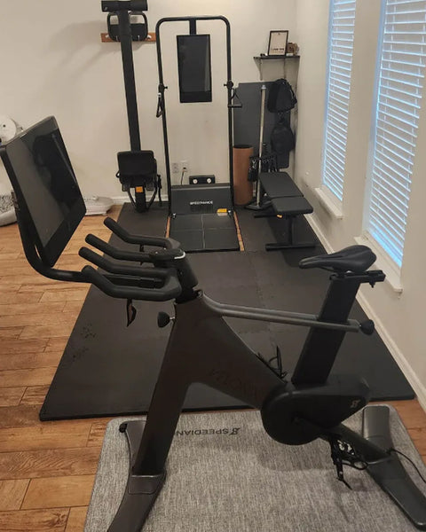 Een Gym Monster in een thuisgym met een hometrainer en een bank