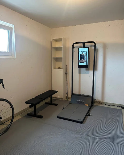 Een Gym Monster in een lichte logeerkamer met een bank en een fiets